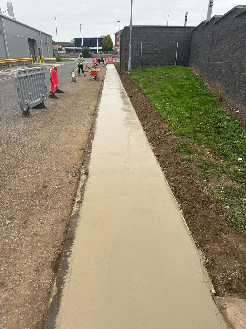 Finished concrete access path with operatives on a commercial site