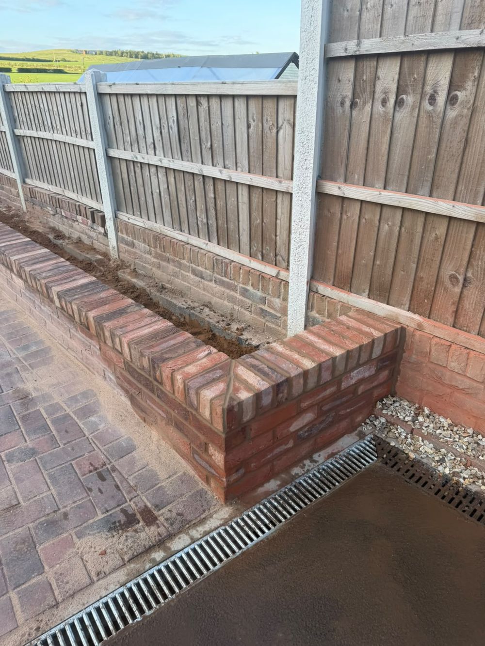 Brick retaining wall with fencing and channel drainage